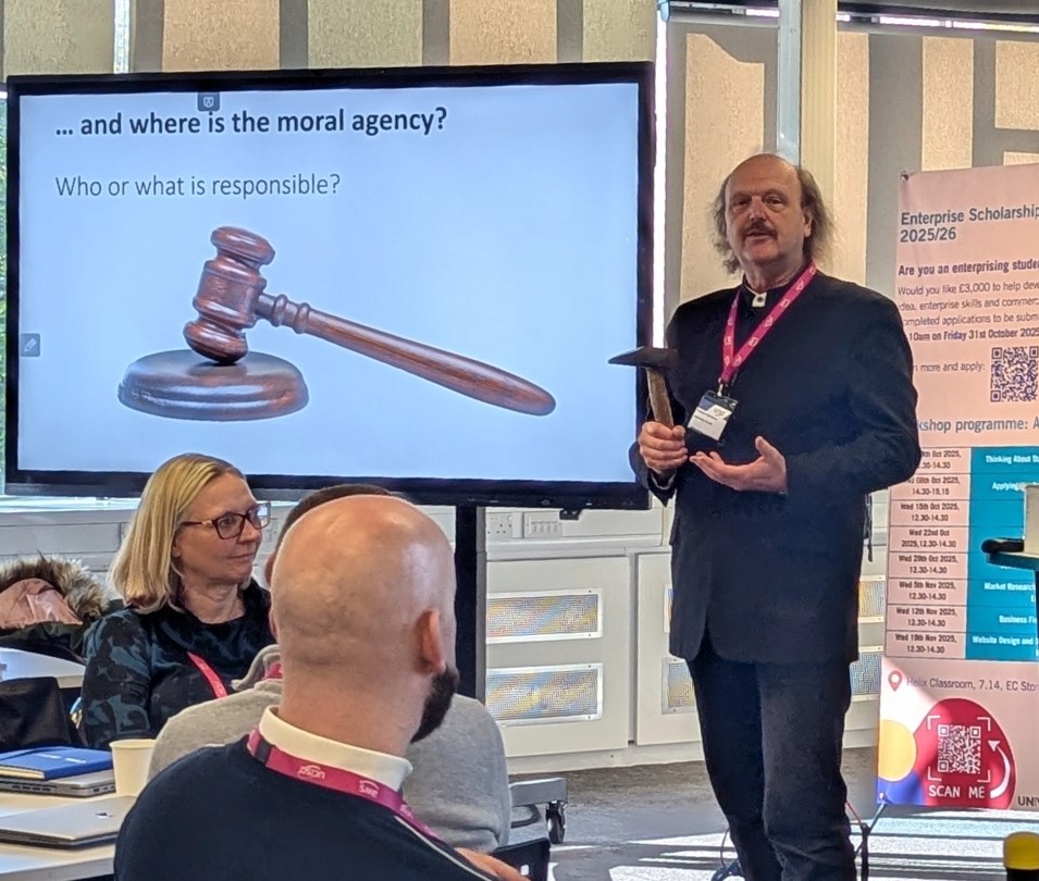 Professor Paul Glover giving his presentation holding a hammer